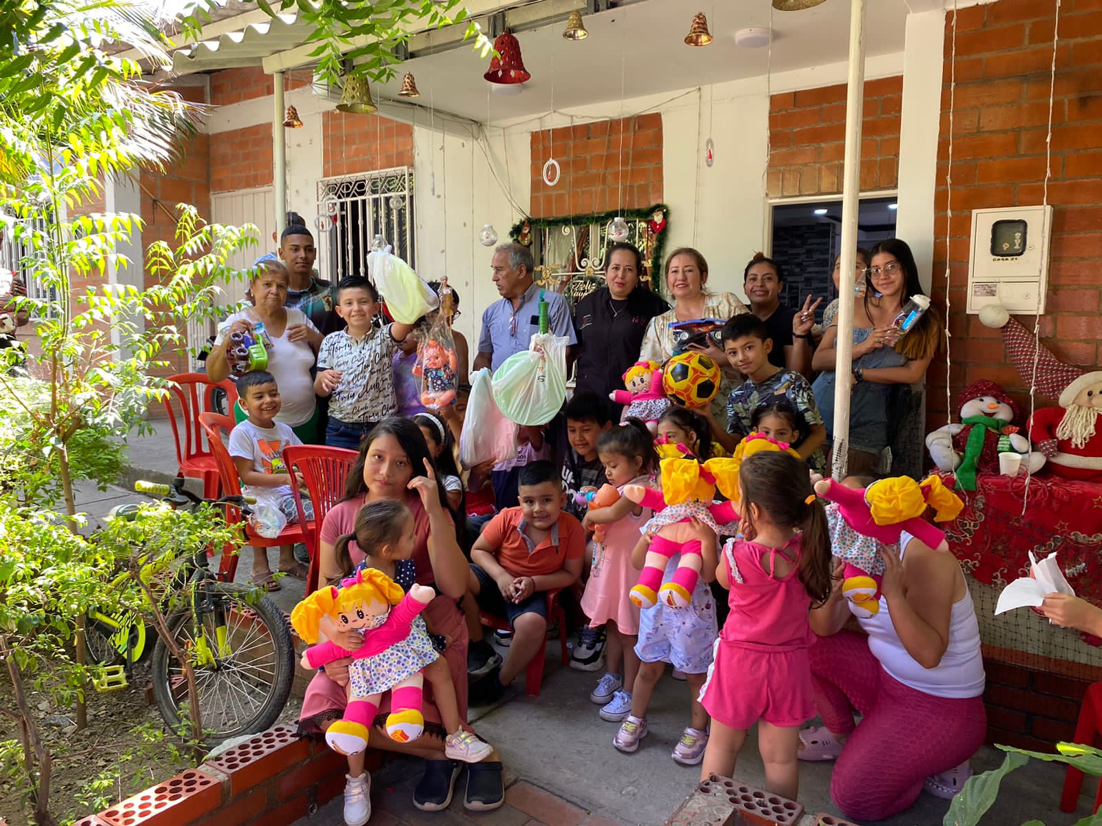 Niños y voluntarios de la Fundación Rosas del Carmelo con muñecas, balones y juguetes recibidos en una entrega de regalos