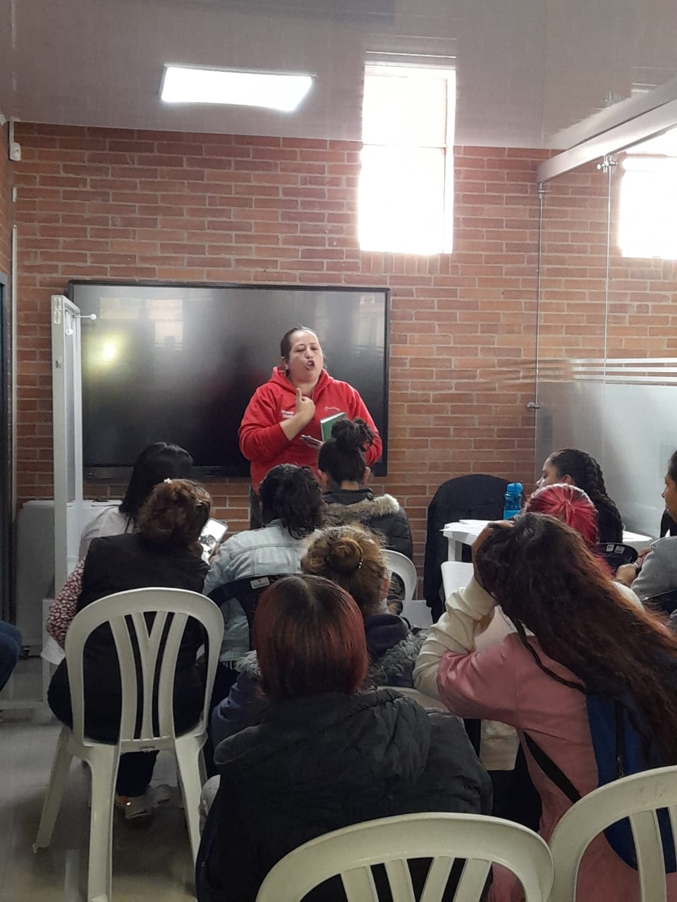Grupo numeroso reunido en espacio comunitario durante actividad del curso de belleza, Bogotá