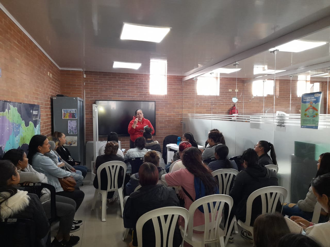 Instructora dando charla del curso de belleza en salón con ladrillo a la vista, Fundación Rosas del Carmelo, Bogotá