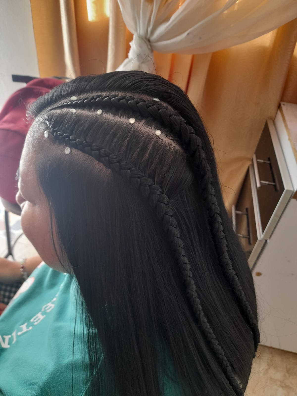 Estudiante del curso de belleza haciendo trenzas de raíz a una compañera, Fundación Rosas del Carmelo