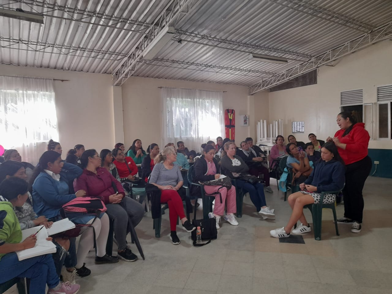Instructora con tapabocas realizando trenzas a una estudiante en el curso de belleza, Fundación Rosas del Carmelo