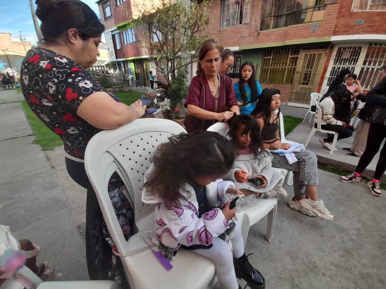 Jornada de peinado comunitario en la calle con vecinos observando, Fundación Rosas del Carmelo, Bogotá