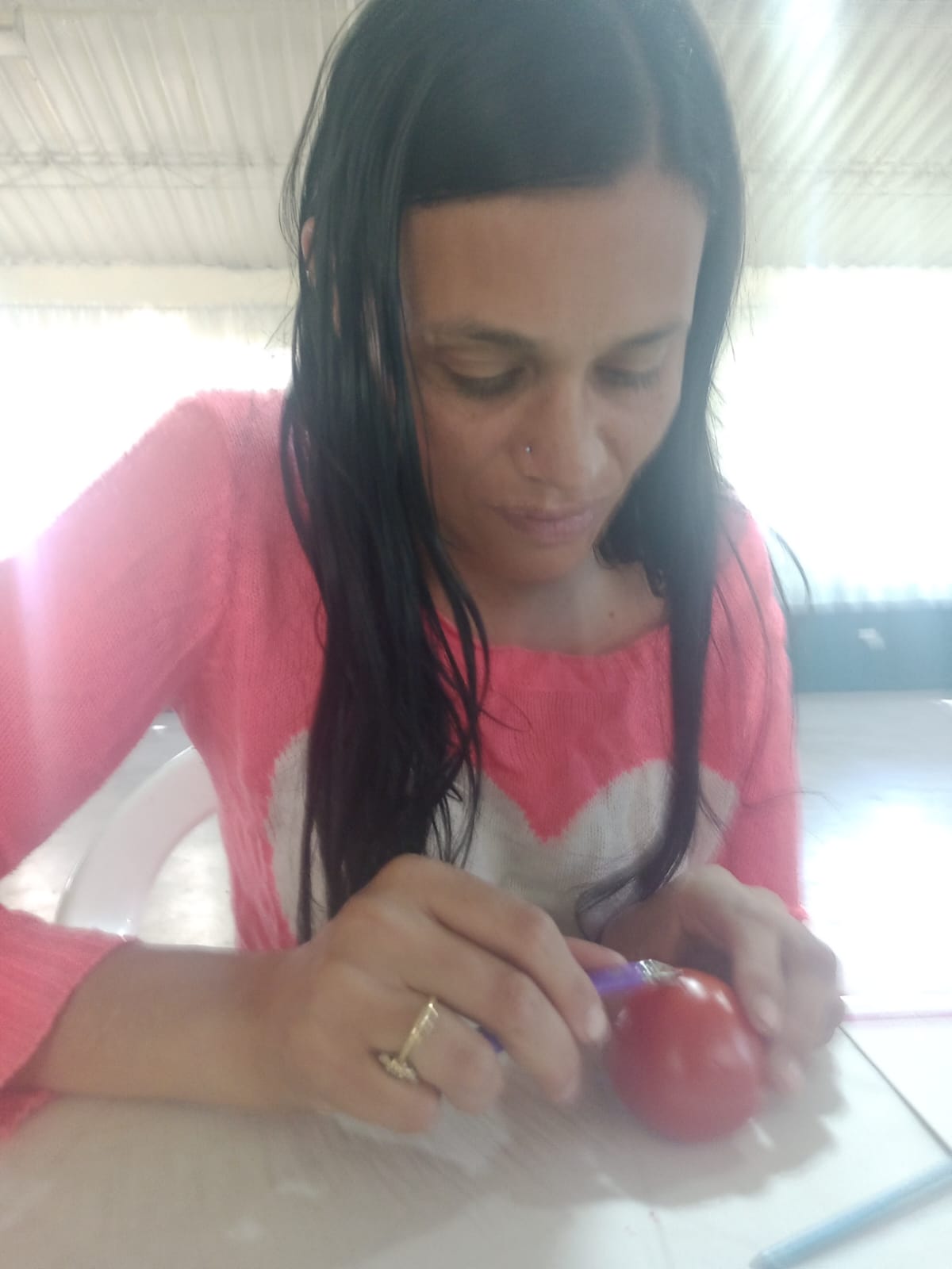 Estudiante con gafas practicando diseño de uñas sobre tomate, curso de manicura, Fundación Rosas del Carmelo