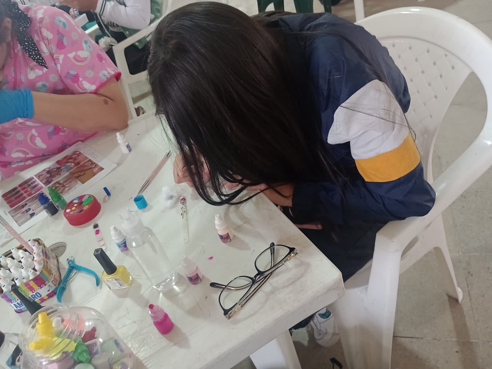 Estudiantes practicando decoración de uñas con esmaltes y pinceles, curso de belleza, Fundación Rosas del Carmelo