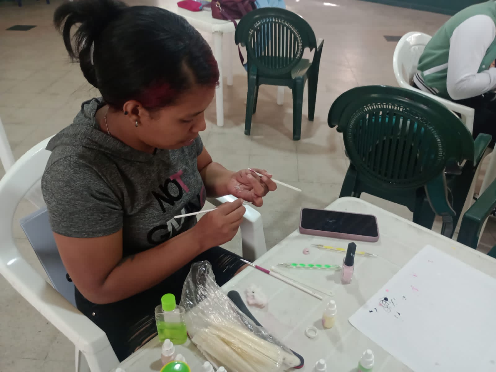 Estudiante aplicando esmalte sobre uña postiza en el curso de manicura, Fundación Rosas del Carmelo