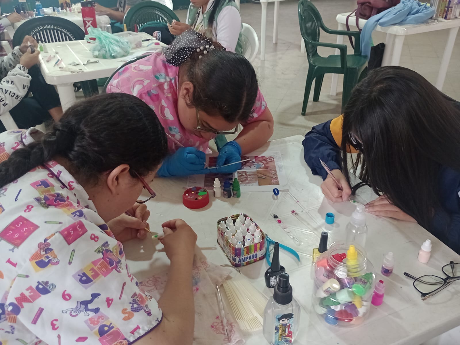 Estudiante practicando manicura sentada junto a mesa con esmaltes, curso de belleza, Fundación Rosas del Carmelo