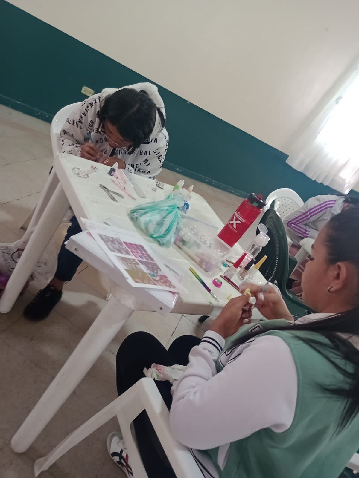 Estudiante con gafas realizando manicura a una compañera, curso de belleza, Fundación Rosas del Carmelo