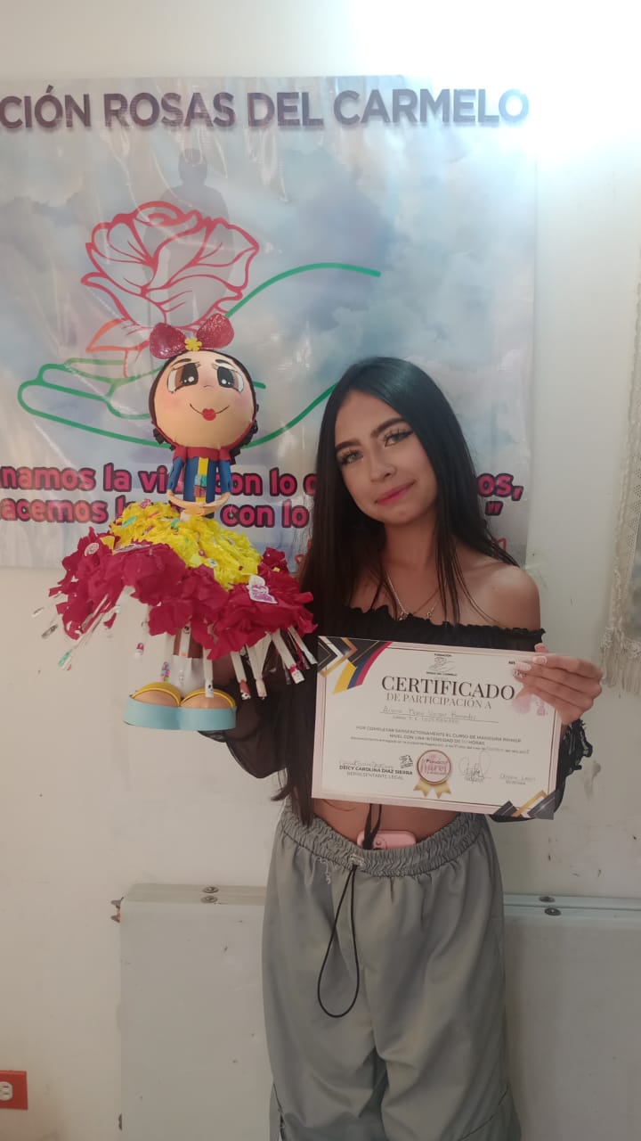 Graduada del curso de manicura sosteniendo certificado y una muñeca decorativa artesanal, Fundación Rosas del Carmelo