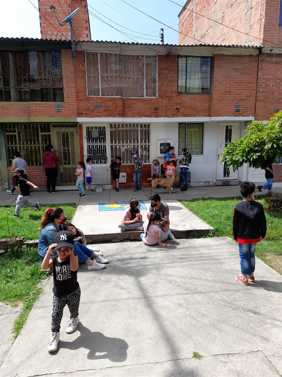 Niños jugando en la calle del barrio mientras adultos conversan durante la jornada de Navidad, Fundación Rosas del Carmelo