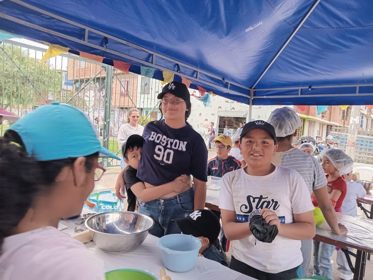 Niños bajo una carpa amasando y preparando galletas en el curso de pastelería, Fundación Rosas del Carmelo, Bogotá