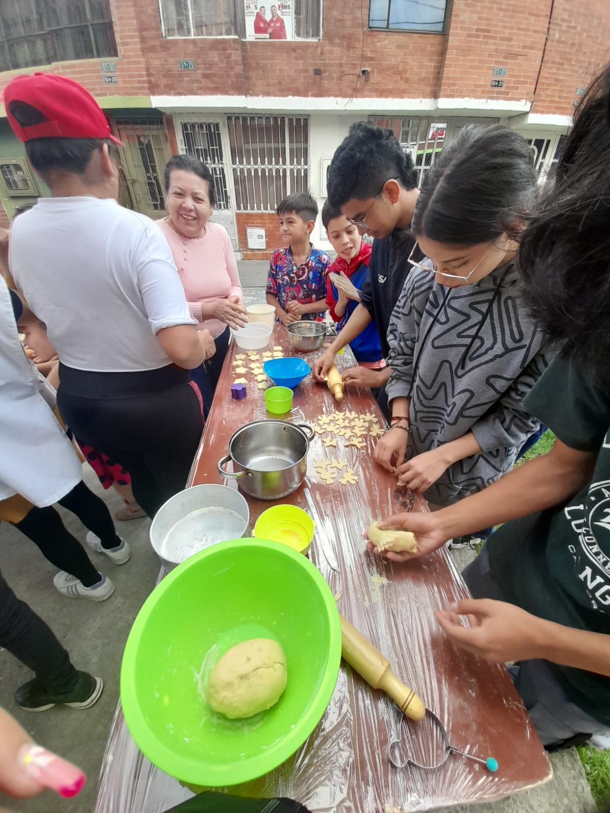 Familias cortando galletas con moldes en forma de estrella y muñeco durante el curso de pastelería, Bogotá