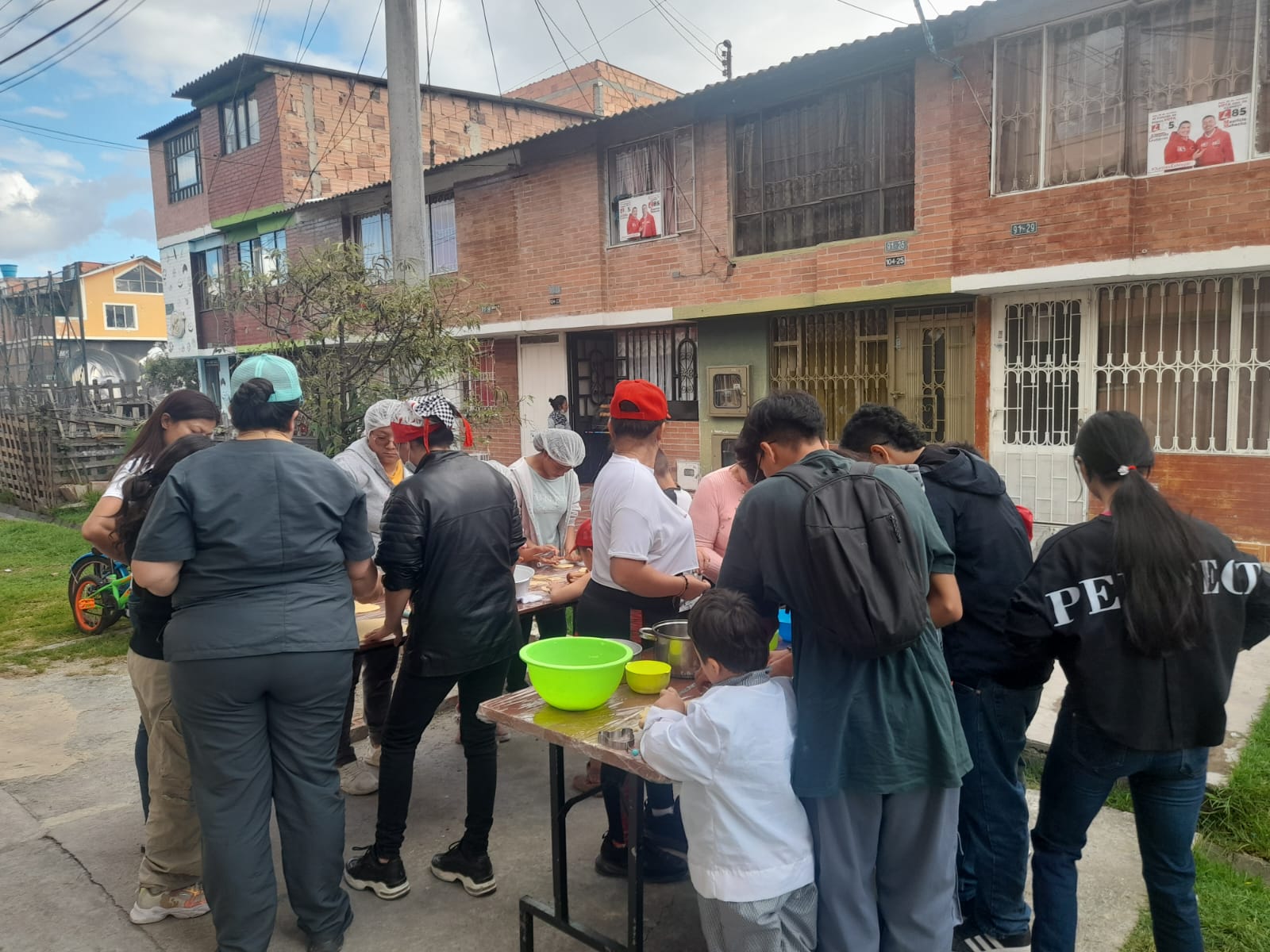 Grupo de niños y jóvenes preparando pastelería en mesa callejera, Fundación Rosas del Carmelo, Bogotá