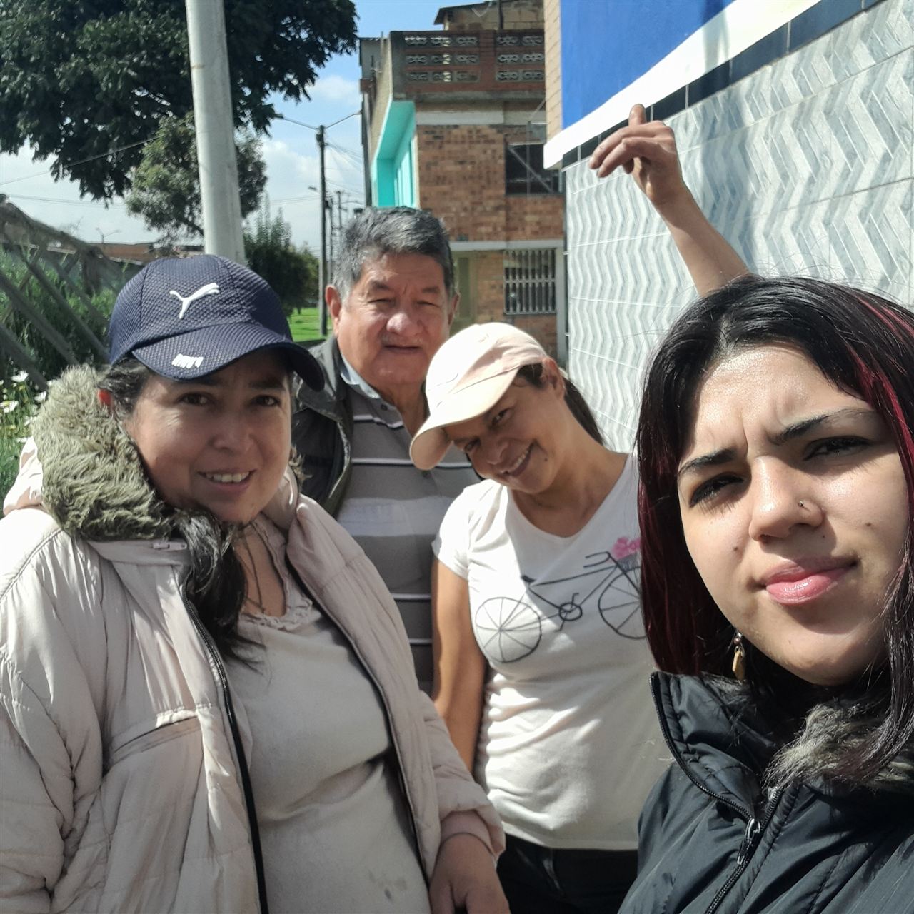 Grupo de voluntarios de la Fundación Rosas del Carmelo posando frente a una vivienda del barrio, Bogotá