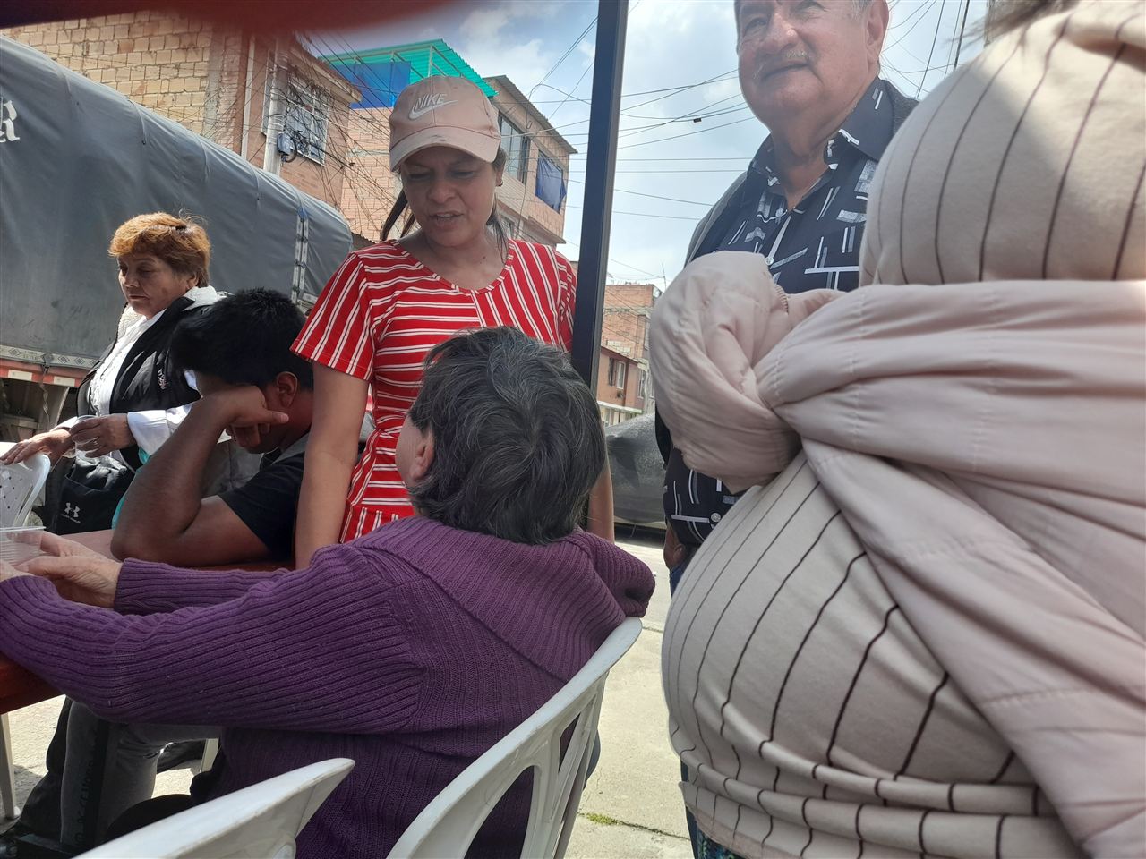 Comunidad reunida conversando bajo una carpa antes del Sancocho Comunitario, Fundación Rosas del Carmelo, Bogotá