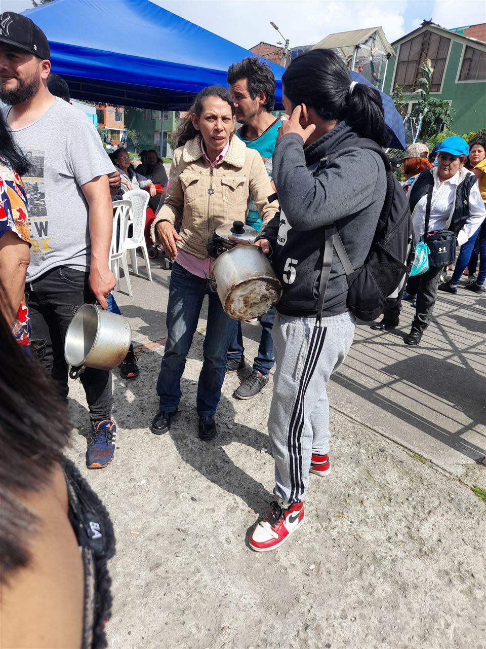 Asistentes caminando con sus ollas para recibir sancocho comunitario, Fundación Rosas del Carmelo, Bogotá