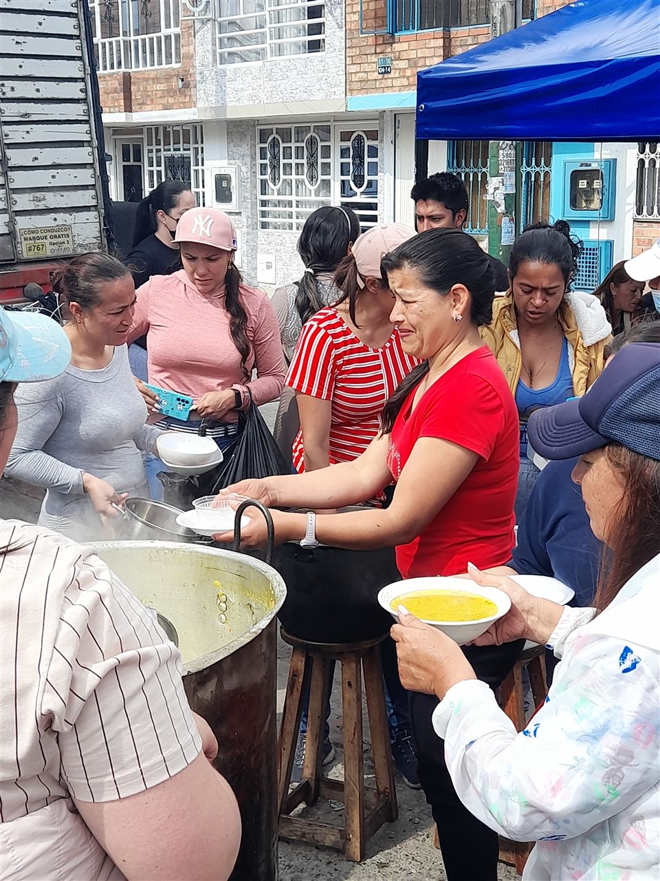 Voluntaria sirviendo sancocho a la comunidad frente a una olla grande, Fundación Rosas del Carmelo, Bogotá