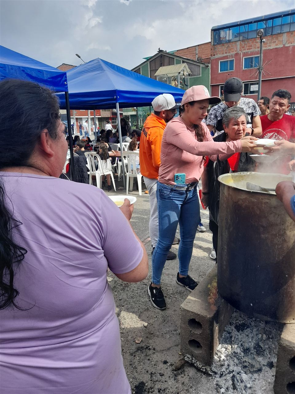 Voluntaria entregando un plato de sancocho a una asistente de la jornada comunitaria, Fundación Rosas del Carmelo, Bogotá