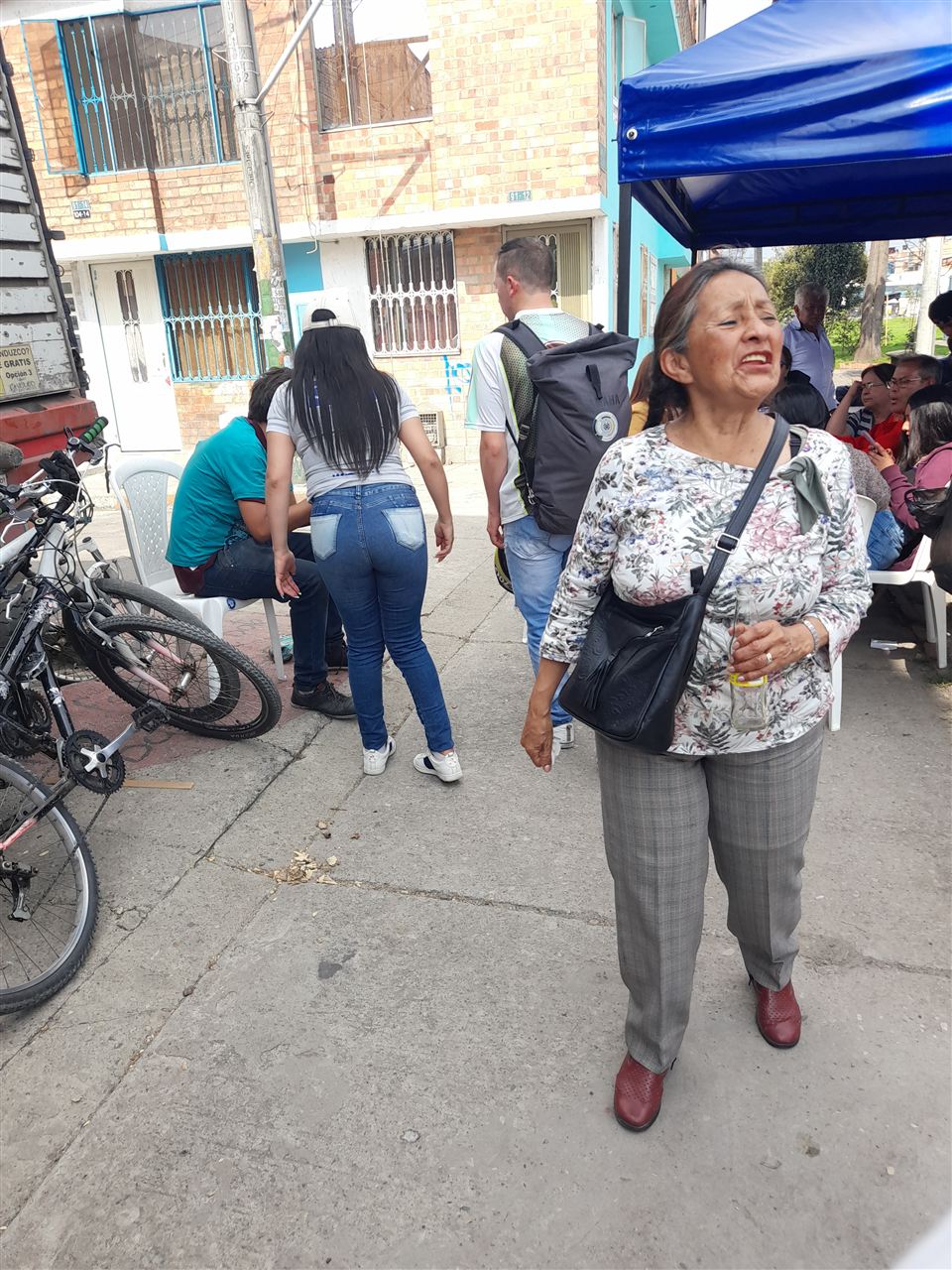Asistente caminando junto a bicicletas estacionadas durante el Sancocho Comunitario, Fundación Rosas del Carmelo, Bogotá