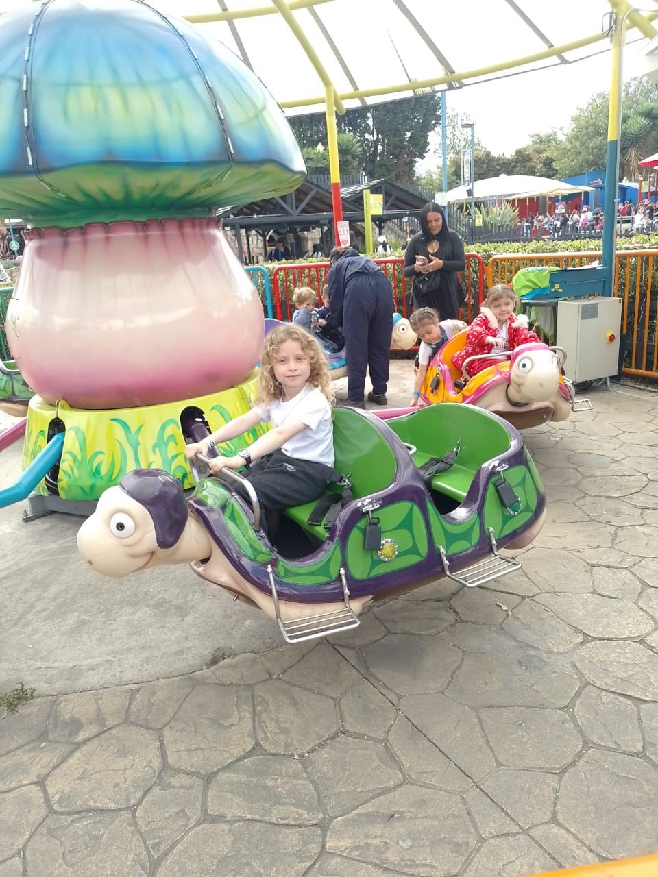 Niños disfrutando del juego de tortugas giratorias en el parque durante las Vacaciones Recreativas, Fundación Rosas del Carmelo