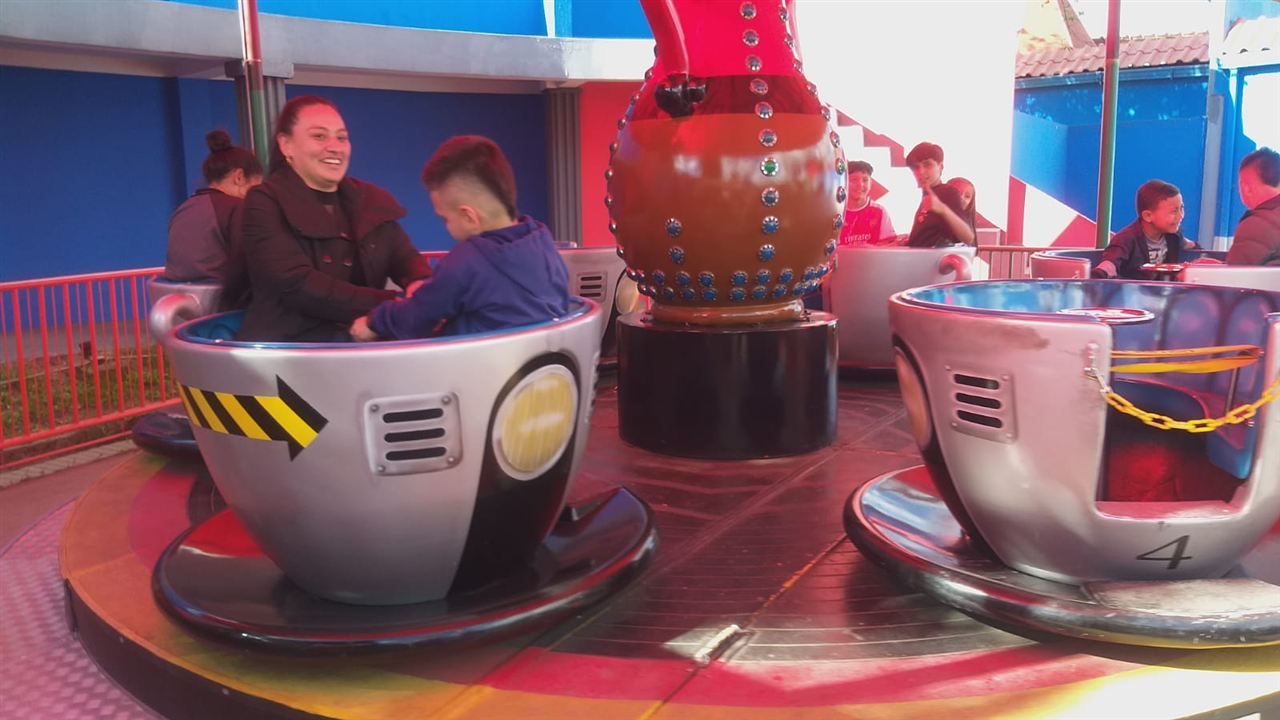 Familia disfrutando del juego de tazas giratorias durante las Vacaciones Recreativas, Fundación Rosas del Carmelo, Bogotá