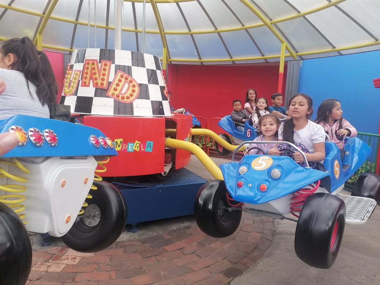 Niños disfrutando del juego de carros voladores durante las Vacaciones Recreativas, Fundación Rosas del Carmelo, Bogotá