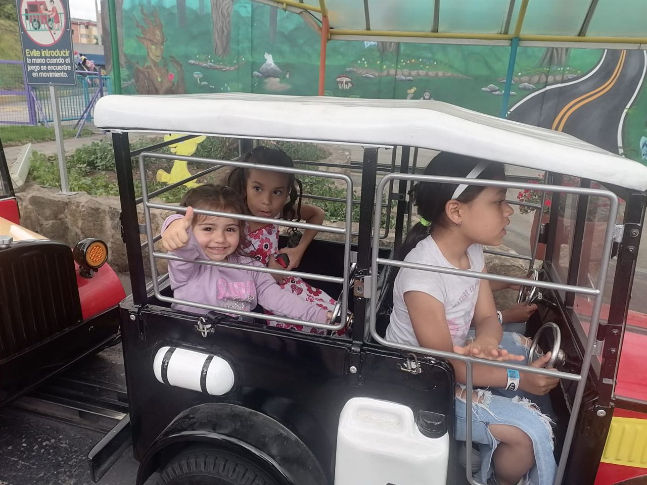 Niñas en un carro antiguo de juguete durante las Vacaciones Recreativas, Fundación Rosas del Carmelo, Bogotá