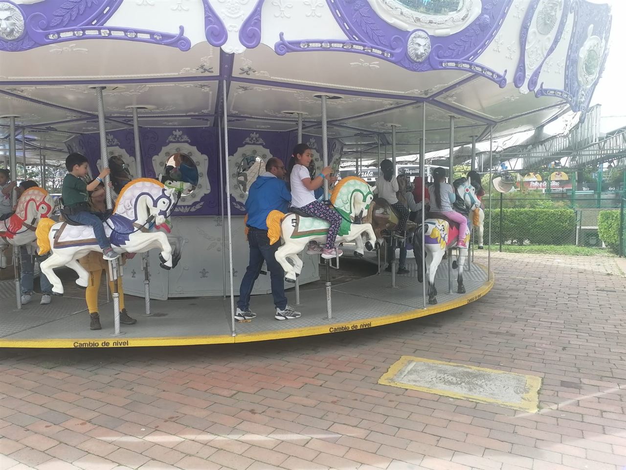 Niños y un adulto disfrutando del carrusel de caballos durante las Vacaciones Recreativas, Fundación Rosas del Carmelo, Bogotá