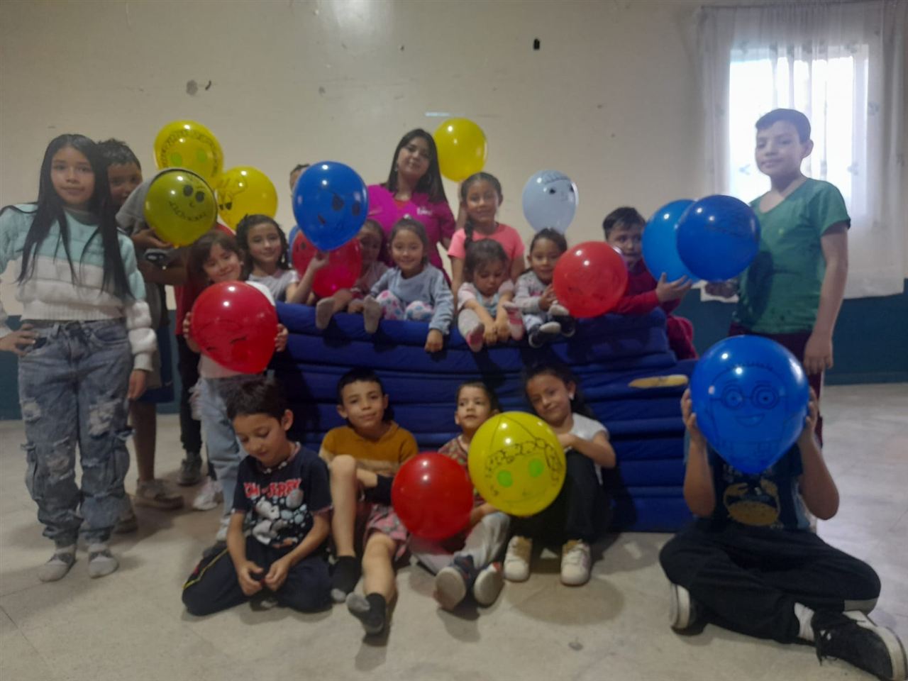 Niños celebrando con globos en actividad recreativa bajo techo, Fundación Rosas del Carmelo, Bogotá