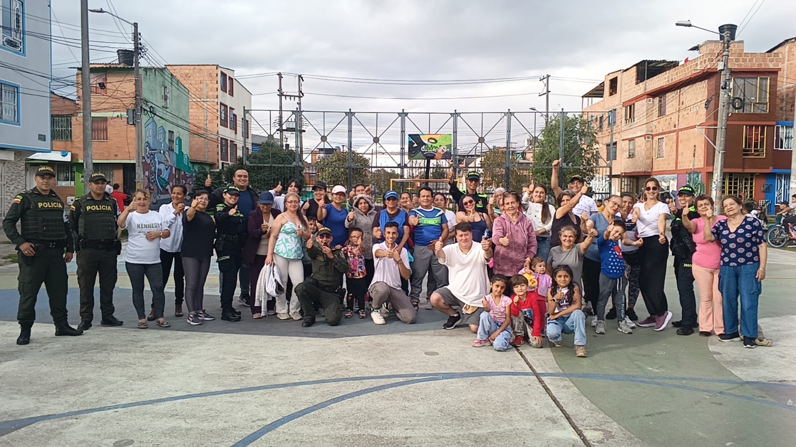 Grupo grande de vecinos y policías posando en cancha comunitaria, Fundación Rosas del Carmelo, Bogotá