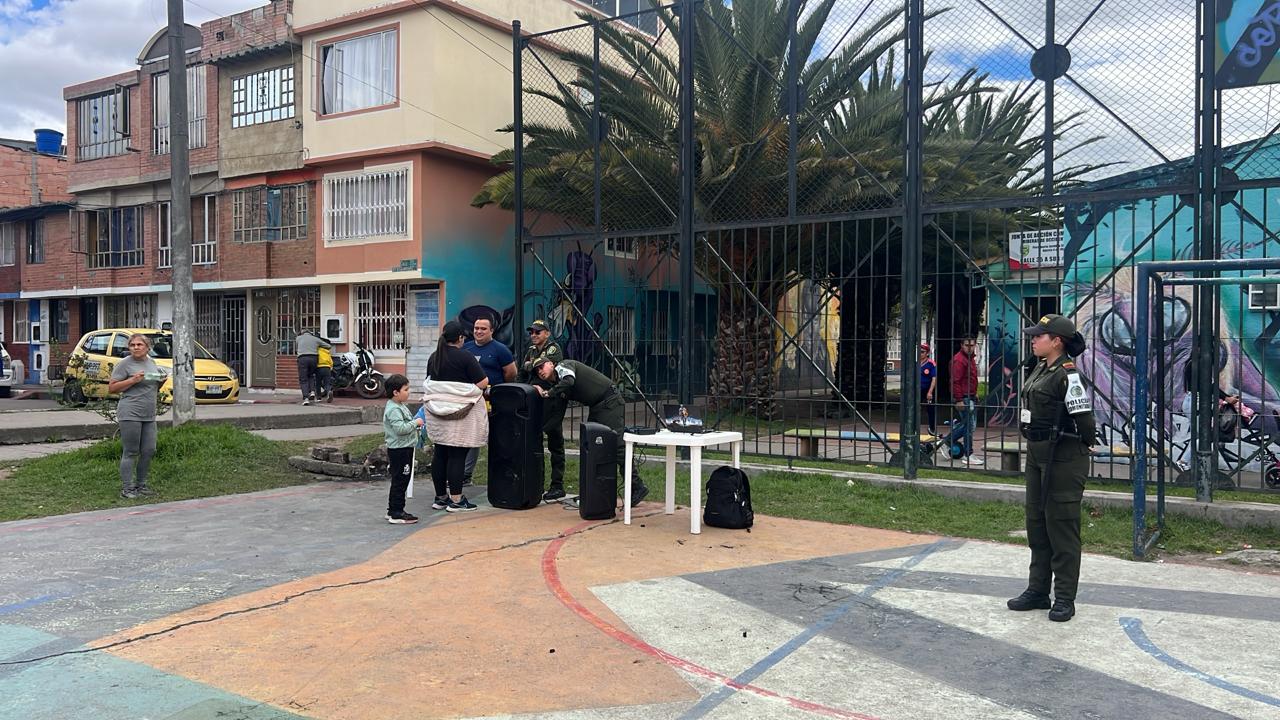 Equipo de sonido y voluntarios preparando actividad comunitaria en cancha, Fundación Rosas del Carmelo, Bogotá